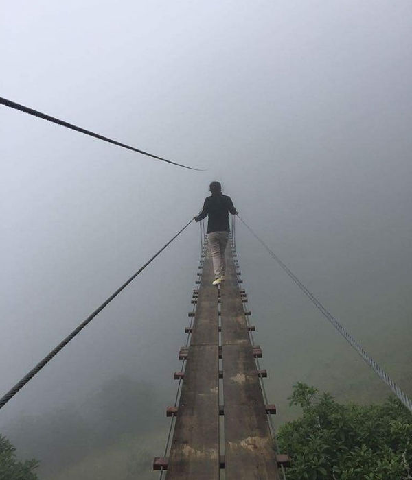 mujer cruzando el puente tibetano entre neblina